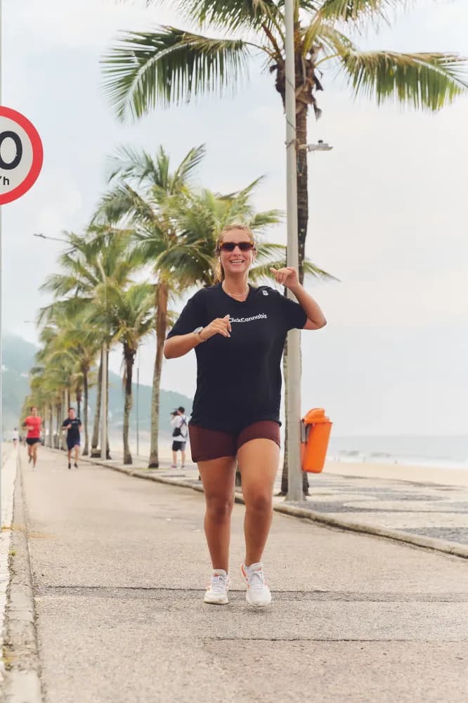 Album do Participante da Click Runner sorri durante corrida na orla com camiseta preta Click Cannabis