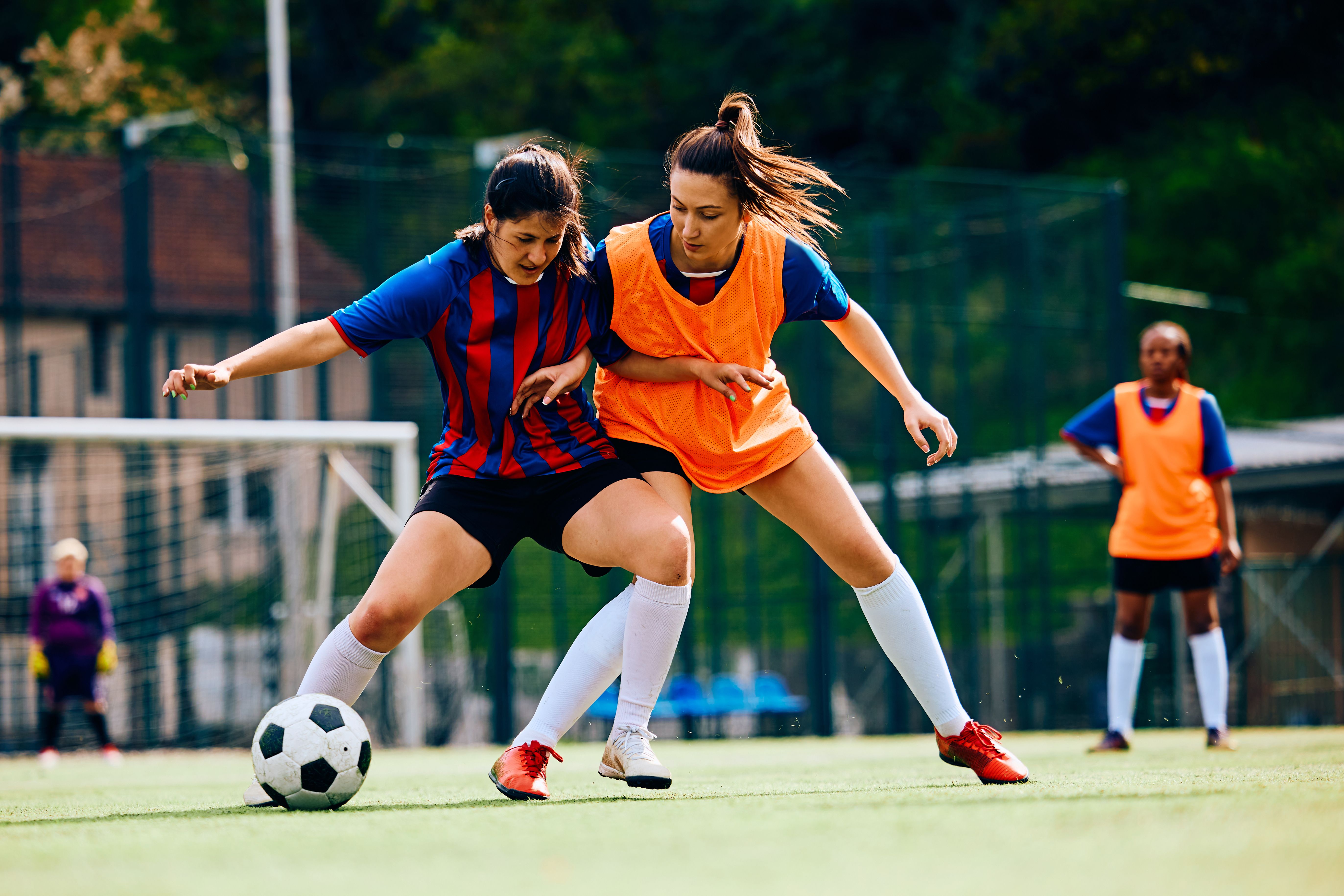 Duas atletas disputam a bola em jogo de futebol feminino, refletindo o debate sobre CBD, THC e regras antidoping nas competições.
