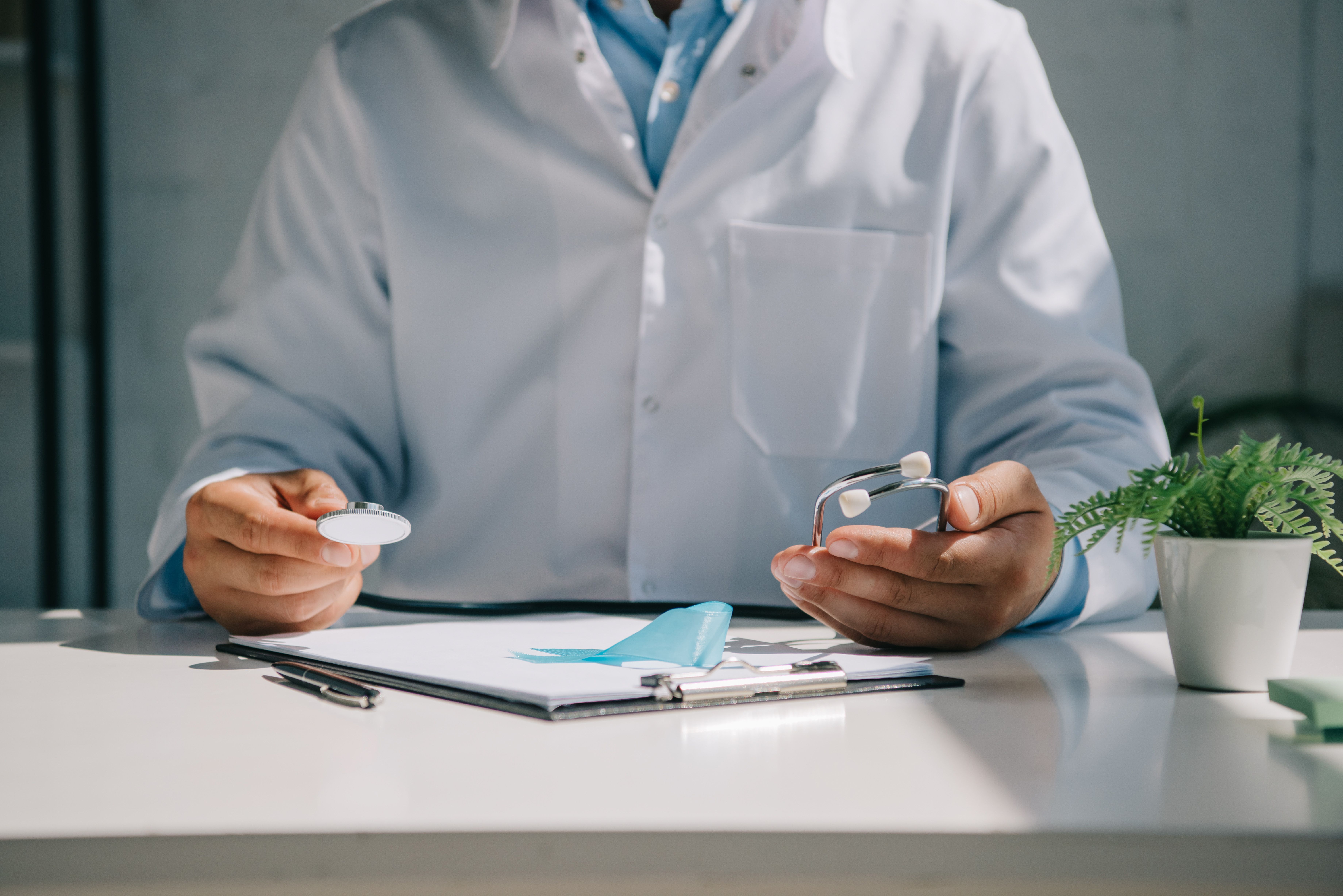 Médico em consulta segurando estetoscópio e analisando prontuário, destacando a relevância da anamnese no atendimento.