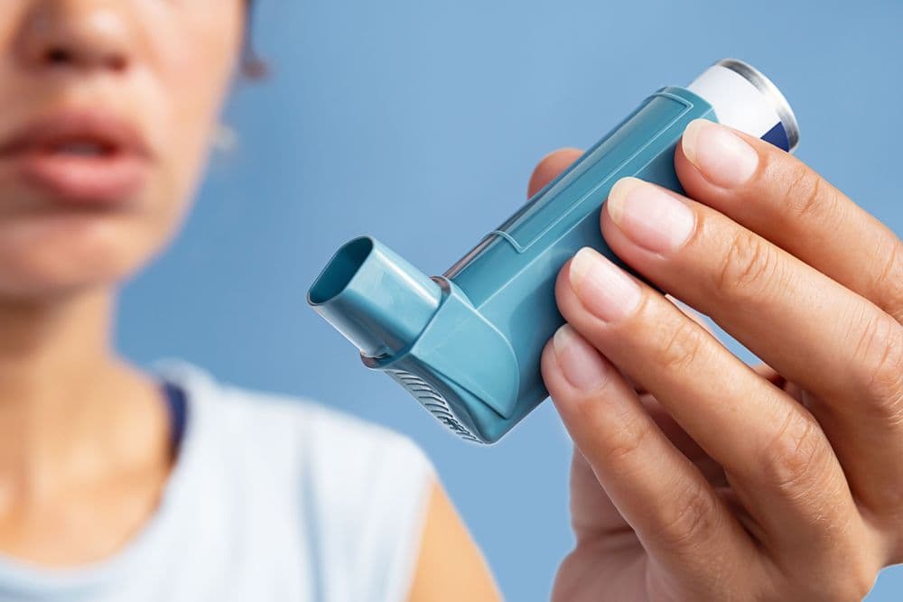 Mulher segurando inalador para asma com foco no dispositivo