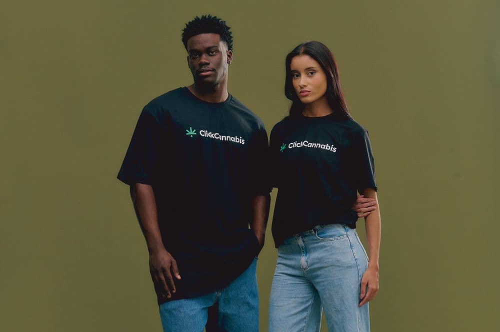Um homem e uma mulher vestindo camisetas pretas da Click Cannabis, em um fundo verde.