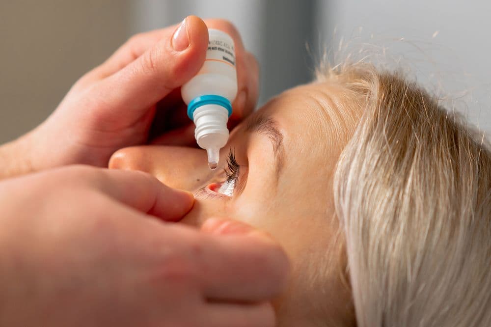 Pessoa aplicando colírio nos olhos durante tratamento ocular